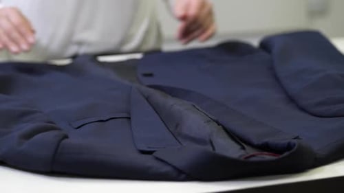 Folding a Dark Blue Suit Jacket on Table