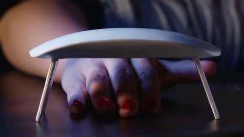 Woman Paints Nails with Red Gel Polish at Home Alone. Uv Led Lamp for Drying Manicure. Modern Method