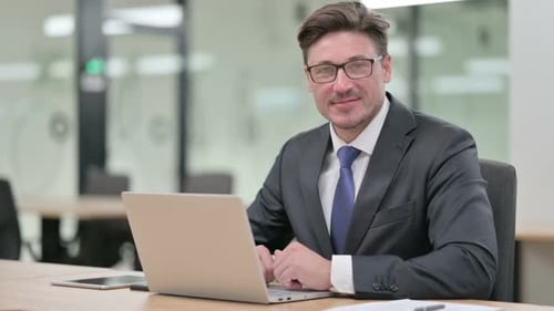 Thumbs Up By Positive Middle Aged Businessman Working in Office