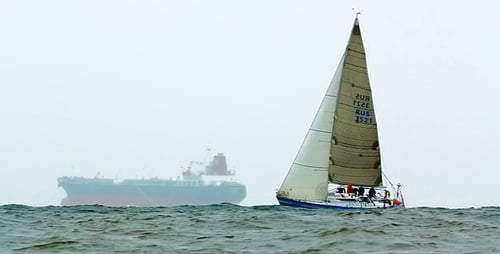 Cargo Ship and Sailing Boat at Sea on Misty Day