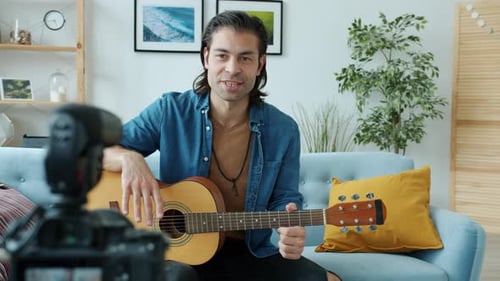 Young Adult Playing Guitar and Recording at Home