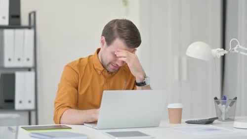 Young Man Having Headache in Office