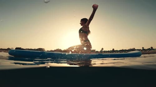 Woman on Paddle Board Doing Yoga at Sunset