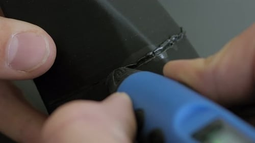 Gros plan de l'ingénieur masculin soudant un objet en plastique avec un stylo 3D