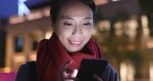 Woman use of mobile phone and hold shopping bag in city at night