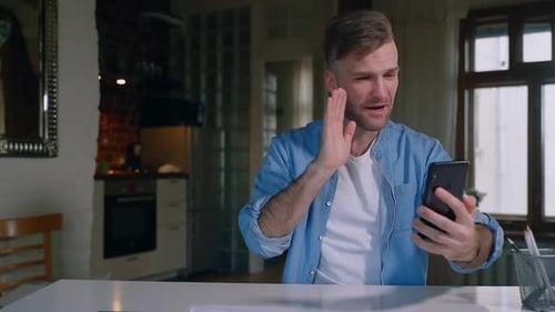 Man Video Chatting on Phone Indoors at Table