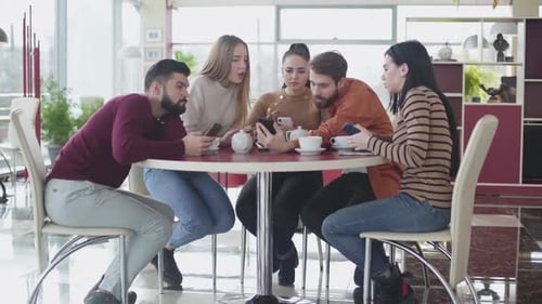 Young Adults Gathered Looking at Smartphone in Cafe