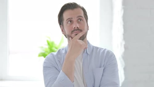 Porträt eines denkenden jungen Mannes, der eine neue Idee bekommt