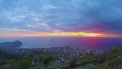 Wunderbarer Sonnenuntergang am Meer, Blick auf die Stadt vom Berggipfel, Zeitraffer für schwere Wolken