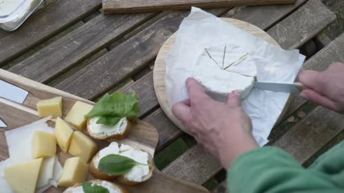 Woman Cuts Brie on Outdoor Picnic Table