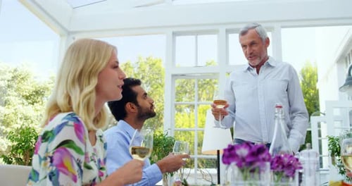 Group of friends interacting with each other while having glasses of wine
