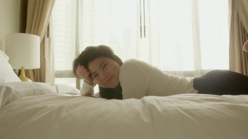 Woman Relaxing in Hotel Room on Bed
