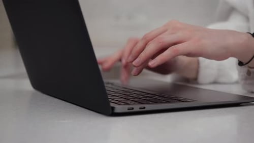 Hands Typing on Laptop Keyboard at Workplace
