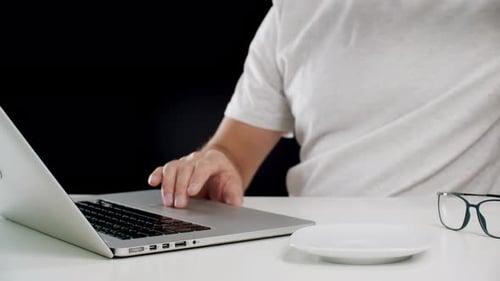 Abgeschnittene Aufnahme eines Mannes, der im Internet surft und Kaffeetasse hält