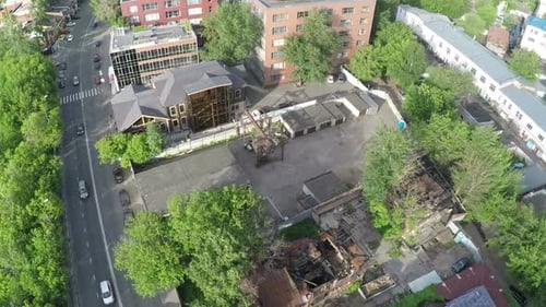 Toma aérea de una calle con tráfico de coches y casa en ruinas