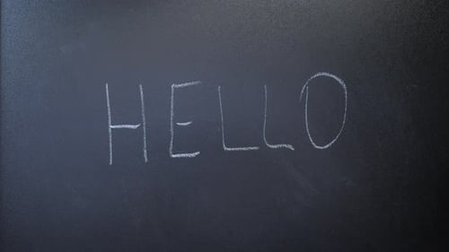 Man writing word hello on chalkboard. Hello word written on blackboard with white chalk