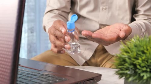 Young Man Using Sanitizer Gel on on Office Desk