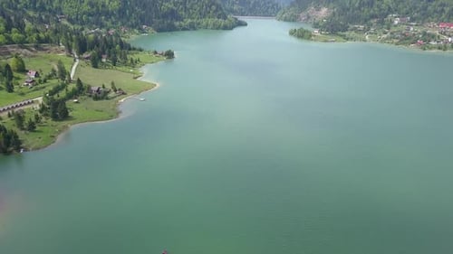 Aerial Upwards pan of Mountain in the distance in Front of Lake with clear skies