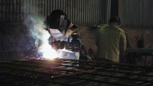 Welder Sparks Metal in Dark Industrial Setting