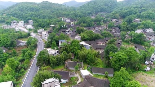 Luftaufnahme eines ländlichen Dorfes, umgeben von grünen terrassenförmig angelegten Reisfeldfarmen im Süden Chinas