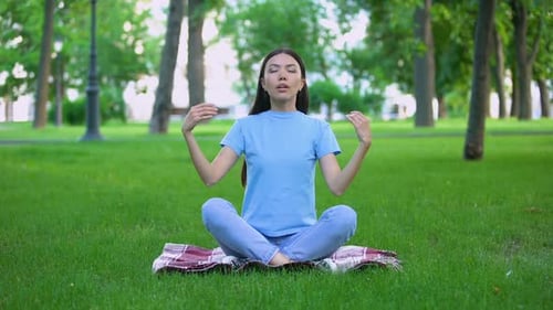 Attractive Young Lady Meditating in Park Sitting Lotus Pose, Relaxing Outdoors