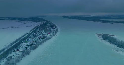Aerial View the Copter Flies Over a Frozen River a Village Stands Along