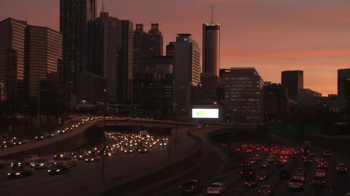 Panning, medium wide, nighttime shot of the Atlanta Skyline with traffic below.