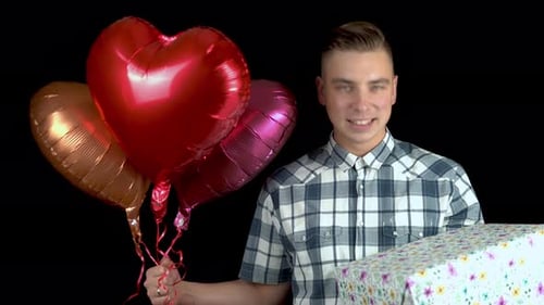 Young Man Holding Balloons and a Wrapped Gift