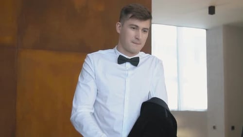 Man Wearing Bow Tie Prepares Jacket Indoors