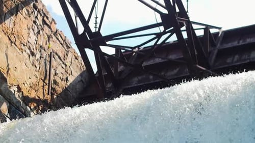 Presa de agua: la corriente de agua cae debajo de una construcción metálica