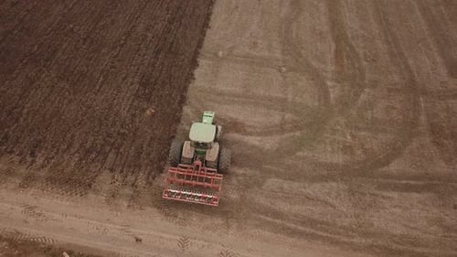 a Large Tractor Plows a Field