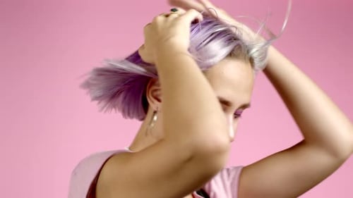 Beautiful Hipster Woman Dancing with Colorful Hairstyle Energetically and Actively on Pink Studio
