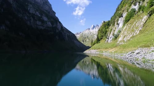 flying over a blue mountain lake in the swiss alps. Mountains reflect in the clear water. alpstein s