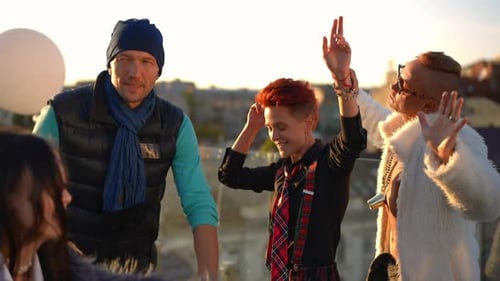 Positive Caucasian and Asian Men and Women Dancing at Golden Sunset on Rooftop in Urban City