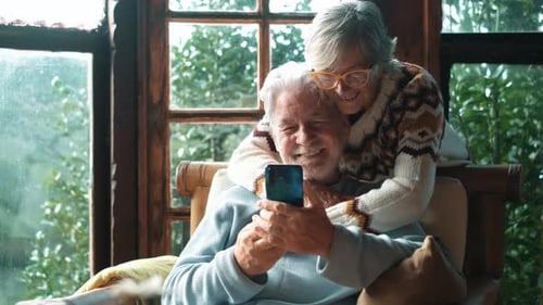 Senior Couple Looking at Phone Smiling Indoors