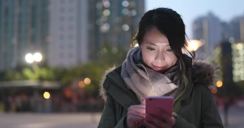 Woman use of mobile phone in city at night