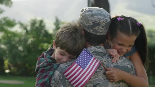 Military Personnel Hugged By Children Holding American Flag