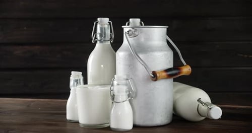 Milk in Bottles and Metal Jug on Wooden Table