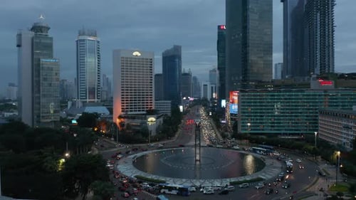 Foto aérea lenta de un tráfico ocupado en una rotonda en el moderno centro de la ciudad de Yakarta, Indonesia