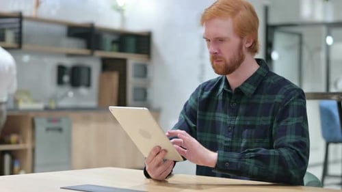 Young Beard Redhead Man Using Digital Tablet in Cafe