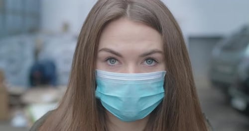 Close-up Face of Girl in Protective Mask Looking at Camera. Young Beautiful Brunette Woman with Grey