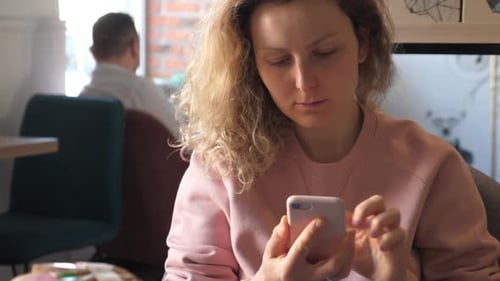 Woman Using a Smartphone in a Cafe.