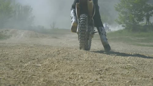 Motocross Racer Start Riding at His Dirt Bike Kicking Up Dirt and Dust