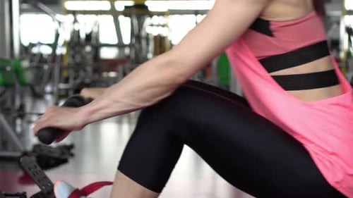 Sportive Woman Works Out on the Simulator in the Gym