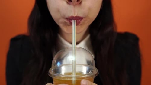 Young Woman Drinking Yellow Beverage with Straw