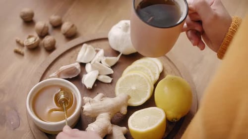 Close up of woman making hot tea with honey