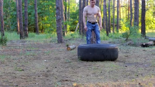 Fit muskulöser Mann, der Crossfit-Übungen macht und große Gummireifen im Freien hebt.