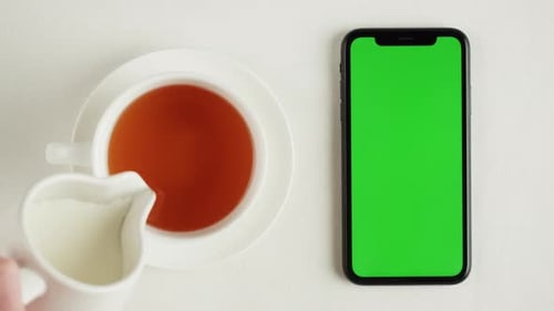 Black Tea with Milk and Green Chroma Key Screen on Smartphone Top View
