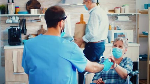 Caregiver Assisting Senior Woman in Wheelchair with Pills