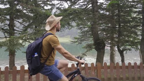 Man riding bike in forest against Lake view.
